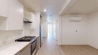 Located at 6559 Brynhurst Ave in the Hyde Park neighborhood of Los Angeles, this thoughtfully designed 2-bedroom, 1-bathroom unit offers a clean, modern aesthetic across a single floor. Light wood-style laminate flooring runs consistently throughout, complementing the crisp white walls and creating a bright, cohesive feel.

The kitchen is well-appointed with two-tone cabinetry — white upper cabinets and gray lower cabinets — paired with white countertops, a stainless steel refrigerator, electric range, dishwasher, and an under-cabinet range hood. Recessed lighting keeps the space well-lit and functional.

A central hallway connects the main living areas, with a wall-mounted mini-split A/C unit providing climate control. The bathroom features light wood-style flooring continuing from the rest of the unit, a white vanity with an integrated sink, a mirror, and clean white walls for a simple, tidy finish.

Both bedrooms are bright and airy, each featuring large windows that invite natural light and offer views of the surrounding Los Angeles neighborhood. One bedroom includes a wall-mounted mini-split A/C unit for additional comfort. The overall layout is efficient and straightforward, making practical use of the available space while maintaining a clean, modern character throughout.