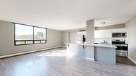 Located at 41 Cowie Hill Rd in Halifax, Nova Scotia, this well-designed one-bedroom, one-bathroom unit offers a smart and efficient use of space across a single floor. The open-concept living and kitchen area serves as the heart of the unit, featuring light-toned laminate flooring throughout and a neutral colour palette that enhances brightness. A large floor-to-ceiling window in the living area floods the space with natural light while framing a scenic view of the surrounding Halifax cityscape and greenery.

The kitchen is thoughtfully appointed with sleek, high-gloss white cabinetry extending to the ceiling, stainless steel appliances including a refrigerator, electric range, built-in microwave, and dishwasher, plus a white countertop peninsula that doubles as a breakfast bar. A white tile backsplash and tile flooring complete the clean, modern aesthetic.

The bedroom is a comfortable, well-lit retreat with its own large window overlooking treetops, light hardwood-style flooring, and a built-in closet. The bathroom is finished in a contemporary style, featuring a white vanity with an integrated sink, a large mirror, tile flooring, and brushed nickel fixtures. Baseboard heating is present throughout, ensuring year-round comfort in this bright, move-in-ready Halifax residence.