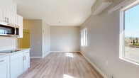 Located at 480 S El Camino Real in Encinitas, California, this single-floor unit offers a clean, modern interior designed for comfort and functionality. The open living area is finished with light wood-tone luxury vinyl plank flooring that runs throughout the space, complementing the neutral gray and white wall palette. Natural light filters in through sliding windows, brightening the open layout and creating an airy, welcoming atmosphere.

The kitchenette is efficiently designed, featuring white shaker-style cabinetry, a built-in cooktop, an over-the-range microwave, and light-toned countertops — all arranged around a compact island-style base unit that maximizes usable space. A wall-mounted HVAC unit provides individual climate control for the living area.

Adjacent to the kitchen, a walk-in closet offers convenient storage, while a full bathroom is thoughtfully equipped with accessibility features including stainless steel grab bars near the toilet and shower, a shower-tub combination, and a vanity with sink. The bathroom's clean white finishes and wood-tone flooring maintain a cohesive look throughout.

The overall design reflects a practical, move-in-ready space suited for those seeking a comfortable, low-maintenance residence in the coastal community of Encinitas.