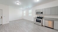 Located at 265 E Old Hickory Blvd in Nashville, TN, this single-story unit offers a practical and efficiently designed layout across two bedrooms and two bathrooms. Light wood-style luxury vinyl flooring runs consistently throughout the space, creating a clean, cohesive aesthetic that complements the bright white walls and white trim found in every room.

The kitchen is a standout feature, equipped with stainless steel appliances including a range, over-the-range microwave, and refrigerator. Gray shaker-style cabinetry pairs with granite-look countertops to deliver a modern, functional workspace. Natural light filters in through multiple windows, giving the open kitchen and living area an airy feel.

Both bedrooms are well-proportioned with white walls, natural window light, and built-in closets featuring bi-fold doors for convenient storage. The primary bedroom includes direct access to an adjoining room or hallway, offering added connectivity within the layout.

The bathrooms maintain the unit's clean aesthetic, with one featuring a glass-enclosed, tiled walk-in shower, grab bars, and wood-style flooring. A hallway connects the main living areas to the bedrooms and bathrooms, keeping the floor plan organized and easy to navigate throughout.
