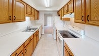 Located at 125 Winslow Dr in Martinsburg, West Virginia, this two-floor residence offers a clean, functional layout designed for comfortable everyday living. The main living area is generously sized, featuring soft wall-to-wall carpeting, recessed lighting, and large windows alongside a sliding glass door that fills the space with natural light and provides views of the surrounding greenery. The galley-style kitchen is efficiently arranged with warm wood cabinetry, white countertops, tile flooring, and white appliances including a range, dishwasher, and refrigerator, with a direct sightline into the living area. Multiple bedrooms are spread across both floors, each featuring plush carpeting, neutral walls, and windows overlooking wooded outdoor scenery. Baseboard heating units are present throughout the bedrooms, ensuring year-round comfort. Closet space is available in the bedrooms, with at least one room featuring a double-door closet. The bathrooms are finished with tile flooring and include a full tub-shower combination as well as a vanity with wood cabinetry and a broad mirror. Clean white walls and consistent neutral tones throughout give the entire residence a bright, cohesive aesthetic that is move-in ready.