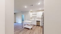 Located at 530 Martin Rd SW in Huntsville, Alabama, this single-story, 2-bedroom, 2-bathroom unit offers a clean, modern aesthetic throughout. The open-concept kitchen and living area forms the heart of the space, with light wood-style flooring, recessed lighting, and a neutral color palette creating a bright, cohesive atmosphere. The kitchen is well-appointed with white shaker-style cabinetry, open shelving, stainless steel appliances including a refrigerator, range, microwave, and dishwasher, and light countertops that complement the overall design.

The living room features a ceiling fan, a glass-paneled exterior door, and a large window that allows generous natural light to fill the room. Both bedrooms are carpeted and offer a calm, comfortable feel, with windows providing additional natural light. The primary bedroom connects to a full bathroom featuring a double-sink vanity with white cabinetry, a large mirror, and a tub-shower combination. A dedicated walk-in closet with wire shelving provides ample storage.

A separate laundry room houses a full-size washer and dryer, adding everyday convenience. The unit's consistent use of light tones and modern fixtures throughout gives the space a fresh, move-in-ready appeal.