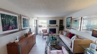This single-story home at 4927 Wild Holly Ln in Arlington, TX presents a well-organized layout with distinct living spaces connected by an efficient floor plan. The living room serves as the central gathering area, featuring a tiled fireplace as its focal point, light wood-style flooring, a textured ceiling, and a sliding glass door that brings in natural light and provides outdoor access. Built-in shelving flanks the fireplace, offering functional display space.

The kitchen is equipped with dark cabinetry, a mosaic tile backsplash in warm tones, light-colored countertops, a double-basin stainless steel sink, and black appliances. A pass-through window visually connects the kitchen to the dining area, which accommodates a full-sized rectangular dining table with a ceiling fan overhead, creating a practical and comfortable space for meals.

The bedroom offers a calm, neutral atmosphere with carpeted flooring, a ceiling fan, and a walk-in closet providing generous storage. The bathroom includes a tub-shower combination with a curved curtain rod, a speckled vanity countertop, and updated fixtures. Throughout the home, the consistent use of light tones and wood-style flooring contributes to a cohesive and inviting overall ambiance.