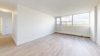 Located at 59 Concession St in Cambridge, Ontario, this two-bedroom, one-bathroom unit offers a clean, modern aesthetic across a well-organized single-floor layout. Light wood laminate flooring runs throughout, complementing the crisp white walls and bright, airy atmosphere found in every room.

The entryway leads into a central hallway that connects all principal areas efficiently. The kitchen features white cabinetry, dark countertops, classic white subway tile backsplash, and stainless steel appliances, including a refrigerator, microwave, and dishwasher. An adjacent dining area flows naturally into the spacious living room, which is bathed in natural light through large windows and provides direct access to a private balcony with open views of the surrounding Cambridge landscape.

Both bedrooms are well-proportioned, each equipped with large sliding-door closets offering generous storage. The primary bedroom is notably spacious, with wide windows framing pleasant outdoor views and a baseboard heating unit beneath. The second bedroom mirrors this layout with its own closet and natural light.

The bathroom is finished with a full soaker tub surrounded by gleaming white subway tile, maintaining the unit's consistent clean and contemporary style. With four closets in total and a thoughtful layout, this unit balances functional living with modern design.