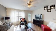 Located on October Road in Clarksville, Tennessee, this single-story residence offers a well-organized layout designed for comfortable everyday living. The floor plan, visible in the 3D overview, reveals a thoughtful arrangement of living, sleeping, kitchen, and bathroom spaces that flow naturally from one area to the next.

The living room serves as the heart of the home, featuring wood-look flooring, abundant natural light from multiple windows dressed with sheer curtains and blinds, and a ceiling fan with light fixture overhead. A glass door leads directly to a private balcony, extending the living space outdoors and enhancing the sense of openness. An accent wall in a deeper gray tone adds visual depth to the room.

The galley-style kitchen is lined on both sides with light wood cabinetry and ample counter space, providing efficient storage and workspace. White appliances, including a refrigerator, range, microwave, and dishwasher, are cleanly integrated throughout. Wood-look flooring continues here, maintaining a cohesive aesthetic.

The bedrooms are carpeted and well-proportioned, each accommodating a full-sized bed with room to spare. Natural light filters in through large windows with sheer coverings. The bathroom features wood-look flooring, a curved shower rod, a tub-shower combination, and a vanity with light wood cabinetry and warm countertops, completing the home's functional and inviting character.