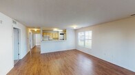Located at 4300 Collegiate Way in Mount Pleasant, Michigan, this single-floor unit offers a practical and functional layout well-suited for everyday living. The open-concept living area features warm hardwood-style flooring and is filled with natural light from multiple windows, including a glass exterior door that provides views of the surrounding greenery. A half-wall peninsula separates the living space from the kitchen, which is equipped with light wood cabinetry, laminate countertops, a full suite of white appliances including a range, microwave, dishwasher, and refrigerator, and a stainless steel sink positioned beneath a window. The bedrooms are carpeted for comfort and each includes a sliding-door closet with built-in shelving, offering ample storage. Windows in each bedroom bring in natural light and outdoor views. The bathroom features dual sinks set into a light wood vanity with a large wall mirror above, hardwood-style flooring, and a separate water closet housing a full tub-shower combination. Textured ceilings are present throughout the common areas, adding subtle visual interest. The overall layout is efficient and well-organized, making this unit a comfortable and functional living space.