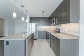 Located at 905 Southdale Rd W in London, Ontario, this well-appointed 2-bedroom, 2-bathroom unit offers a thoughtfully designed single-floor layout with a clean, contemporary aesthetic throughout. Wide-plank hardwood-style flooring flows through the main living areas, complemented by neutral tones and crisp white trim that create a bright, welcoming atmosphere.

The open-concept kitchen is a standout feature, showcasing rich dark-toned cabinetry, granite-style countertops, stainless steel appliances, and a large island with seating — all illuminated by elegant pendant lighting. The kitchen connects seamlessly to the dining area and living room, which is anchored by large sliding glass doors leading to a private balcony with views of the surrounding neighbourhood.

The generously sized primary bedroom features light laminate flooring, a large window for natural light, and a double-door closet. The second bedroom is equally comfortable, with hardwood-style flooring and access to the hallway. Two well-finished bathrooms serve the unit — one with a tiled walk-in shower and the other with a full soaker tub, both featuring tile surround with decorative accents and granite vanity tops. In-suite laundry adds everyday convenience to this modern, move-in-ready home.