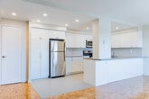 Located at 434 William St in Cobourg, Ontario, this 2-bedroom, 1-bathroom unit offers a well-organized single-floor layout that makes efficient use of its space. The living room is a bright and open area anchored by warm parquet flooring that extends throughout the unit, with large windows and a sliding glass door providing access to a private balcony and filling the room with natural light and outdoor views of the surrounding neighbourhood.

The kitchen is clean and modern, featuring white shaker-style cabinetry that extends to ceiling height, stainless steel appliances including a refrigerator, electric range, and over-the-range microwave, and a peninsula counter that separates it from the living area. The light-toned countertops and recessed lighting contribute to a bright, functional workspace.

Both bedrooms are comfortably sized with neutral walls, parquet flooring, baseboard heating, and windows that bring in natural light. The primary bedroom benefits from a sliding glass door connecting to the balcony, adding a sense of openness.

The bathroom is well-appointed with a frameless sliding glass shower enclosure with white tile surround, a granite-topped vanity, and tile flooring, lending a clean and contemporary finish to the space. A hallway and closet round out the layout, providing practical storage and circulation throughout the unit.