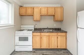 Located at 2018 Cliffview Rd in Cleveland, OH, this single-floor unit offers a straightforward, functional layout designed for comfortable everyday living. The floor plan flows from an entry foyer with hard-surface flooring into a generously sized living area finished with warm, neutral-toned carpeting. The open feel of the living space is reinforced by clean, light-gray walls and a well-proportioned entry door that anchors the room.

The kitchen is equipped with honey-toned wood cabinetry extending both above and below the counters, providing ample storage. Dark, marbled countertops add visual contrast, while a white gas range and a stainless steel sink complete the practical setup.

The bedrooms are carpeted and bathed in natural light through multiple windows fitted with blinds. Ceiling fans are present in several rooms, offering efficient air circulation. The rooms maintain a neutral palette that lends versatility for personalization.

The bathroom features wood-look vinyl plank flooring, a tiled tub-and-shower surround with large-format beige tiles, a built-in window for natural light, and a wood-toned vanity. Overall, the unit presents a clean, functional interior with consistent finishes throughout.