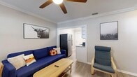 This single-story unit offers a thoughtfully designed layout that balances comfort and functionality across its main living spaces. The open living and dining area serves as the heart of the home, featuring light wood-look flooring, crown molding, and a ceiling fan overhead. A wall-mounted TV anchors the living space, while a bright window fitted with blinds allows natural light to filter in. The dining area comfortably accommodates a four-person table, making it ideal for everyday meals or casual gatherings.

The kitchen is well-equipped with stainless steel appliances, including a full-size refrigerator and electric range, complemented by granite countertops and white cabinetry. A window and secondary door provide additional light and ventilation.

Both bedrooms are generously proportioned, each featuring crown molding, ceiling fans, light wood-look flooring, and windows with blinds that bring in natural light. Each room also includes access to a walk-in closet with built-in shelving, offering ample storage. The bedrooms are versatile, with space for both sleeping and a dedicated workspace, making them well-suited for a variety of living arrangements. The overall aesthetic throughout the unit is clean, neutral, and move-in ready.