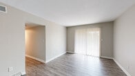 Located at 2903 W 42nd Ave in Kansas City, Kansas, this single-floor residence offers a thoughtfully updated interior with a clean, neutral color palette throughout. The open living area is finished with durable luxury vinyl plank flooring in a warm gray tone, complemented by crisp white baseboards. A large sliding glass door dressed with vertical blinds allows generous natural light to fill the space while providing access to the outdoors. The layout flows seamlessly between the living area and adjacent spaces, connected by open archways that enhance the sense of openness. The kitchen is well-appointed with white shaker-style cabinetry, dark countertops, a stainless steel range, and a stainless steel sink, all set atop matching LVP flooring that ties the common areas together cohesively. The bedrooms feature plush wall-to-wall carpeting, ceiling fans with light fixtures, and ample closet storage. Multiple windows in the bedrooms invite natural light and offer views of the surrounding neighborhood. The unit's consistent neutral tones and updated finishes create a clean, move-in-ready environment suitable for a variety of living arrangements. Overall, the space presents a practical and well-maintained layout with modern touches throughout.