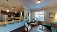This well-appointed one-bedroom, one-bathroom residence in Conroe, TX offers a thoughtfully designed single-level layout that balances comfort and style. Crown molding runs throughout the home, adding a refined architectural detail to each room. The open-concept living and dining area is bright and welcoming, with multiple windows dressed in blinds and sheer curtains that allow generous natural light to fill the space. Dark hardwood-style flooring anchors the living area, which offers ample room for relaxed seating arrangements.

The kitchen is a standout feature, equipped with rich dark cabinetry, granite countertops with a tile backsplash, and a full suite of stainless steel appliances including a refrigerator, microwave, and range. A raised breakfast bar provides additional counter space and a casual dining option, while pendant lighting adds warmth overhead.

A separate dining nook accommodates a round dining table, creating a defined space for meals. The bedroom is a calm retreat, featuring large windows that invite natural light, warm neutral tones, and dark hardwood-style flooring. The full bathroom echoes the kitchen's elevated finishes with a granite vanity countertop, dark cabinetry, and stylish pendant lighting above a wide mirror.