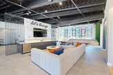 Located at 1 Green Island Boulevard in Worcester, MA, this dynamic amenity floor offers an impressive collection of thoughtfully designed spaces across a single expansive level. The centerpiece is a stylish resident lounge featuring exposed industrial ceilings, a bold "Let's Lounge" wall mural, and oversized sectional seating complemented by a wet bar and large windows that flood the space with natural light and city views. High-backed booth seating and eclectic furnishings create flexible social zones throughout. A dedicated co-working area provides a conference table, pendant lighting, and built-in teal private study pods for focused work. The fitness center is split between a bright, open stretching and cardio room and a vibrant weight room adorned with bold yellow ceilings and a graphic motivational mural, fully equipped with free weights and dual mounted screens. A game room rounds out the interior amenities, featuring a golf simulator, pool table, and a kitchenette with a beverage center. Two outdoor terraces extend the living space further, offering tiled patios with lounge seating, dining areas, string lights, and sweeping views of the Worcester skyline. A well-appointed kitchenette with sleek grey cabinetry and subway tile completes the floor.