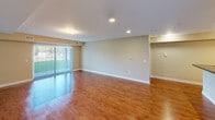 This single-floor residence offers a thoughtfully designed layout across a generous footprint. The open living area features warm hardwood-style flooring, recessed and flush lighting, and a sliding glass door fitted with vertical blinds that invites natural light and provides outdoor views. The space flows seamlessly toward the kitchen, which is separated by a breakfast bar counter.

The kitchen is well-equipped with rich medium-toned wood cabinetry, dark laminate countertops, and a full suite of stainless steel appliances including a refrigerator, electric range, built-in microwave, and a double-basin sink. Track lighting illuminates the workspace throughout. A dedicated laundry area is conveniently located nearby, housing a stacked washer and dryer unit alongside a wall-mounted wire shelf.

The bedroom is carpeted and features a window with outdoor views, providing a quiet retreat. A spacious walk-in closet offers built-in shelving and hanging rods for ample storage. The full bathroom includes a long double-sink vanity with a wide mirror, tile flooring, a soaking tub, and a separate shower, all finished in a clean, neutral palette.