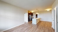 This single-floor residence in Romeoville, Illinois presents a thoughtfully designed open-concept layout that seamlessly connects the living and kitchen areas. Light-toned luxury vinyl plank flooring flows throughout the main living spaces, contributing to a bright, cohesive aesthetic complemented by neutral wall tones.

The kitchen serves as a central hub, featuring rich dark-espresso cabinetry that extends to the upper walls for generous storage. A suite of stainless steel appliances—including a French door refrigerator, microwave, and range—provides modern functionality. A white-topped kitchen island with an undermount sink anchors the space, illuminated by stylish pendant lighting overhead.

The bedroom offers plush carpeting and ample wall space, accessed via a hallway with a bifold closet door for additional storage. Two bathrooms serve the residence: one featuring a soaking tub with shower and dark cabinetry tower, and a second with a glass-enclosed walk-in shower, dark vanity cabinetry, and a white countertop with an undermount sink. Both bathrooms carry the wood-look flooring for a consistent finish.

An attached garage with a concrete floor and automatic opener provides convenient enclosed parking and additional storage capacity.