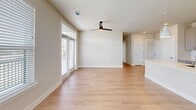Located at 15506 Interplace Rd in San Antonio, TX, this well-appointed one-bedroom, two-bathroom residence offers a thoughtfully designed single-floor layout. The open-concept kitchen and living area serves as the heart of the home, featuring light wood-tone flooring, a ceiling fan, and abundant natural light from large windows and French doors that lead to a private balcony with outdoor views. The kitchen is outfitted with gray shaker-style cabinetry, a geometric white tile backsplash, quartz countertops, stainless steel appliances including a range, microwave, and refrigerator, and a spacious island with an undermount sink. The living area is bright and airy, benefiting from the open layout and multiple windows. The bedroom offers comfortable carpeting, a ceiling fan, a large window with outdoor views, and direct access to a walk-in closet with built-in shelving and hanging rods. Both bathrooms are finished with light wood-tone flooring and feature glass-enclosed tiled shower-tub combinations with brushed nickel fixtures and wall-mounted cabinetry for storage. Clean neutral tones and modern finishes throughout contribute to a cohesive, contemporary ambiance across the entire residence.
