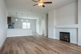 Located on Botanical Drive in Fitchburg, WI, this three-bedroom, three-bathroom townhome is thoughtfully arranged across three floors. The entry level features a welcoming foyer with light-filled living space, luxury vinyl plank flooring, and direct access to an attached garage with a utility area. The main living floor showcases an open-concept layout combining the dining room, kitchen, and living room into one expansive, airy space. The kitchen is appointed with rich dark-stained cabinetry, stainless steel appliances including a refrigerator, range, microwave, and dishwasher, complemented by white quartz countertops and a peninsula island with pendant lighting overhead. A fireplace anchors the living area, which is finished with warm hardwood-style flooring and a ceiling fan. A full bathroom with matching cabinetry and wood-tone flooring completes this level. The upper floor houses all three bedrooms, each with plush carpet, ceiling fans, and ample natural light from large windows. Closets with bifold doors provide generous storage. The floor also includes a dedicated laundry room and additional bathrooms. A utility room with electrical panels rounds out the lower level, offering practical functionality throughout this well-designed home.