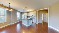 Located at 3170 Centennial Ridge in Grand Rapids, Michigan, this single-floor home offers a well-designed open-concept layout that seamlessly connects the kitchen, dining, and living areas. The kitchen is a standout feature, showcasing crisp white cabinetry with dark hardware, a curved center island with a built-in sink and pendant lighting overhead, and a full suite of stainless steel appliances including a gas range, over-the-range microwave, and refrigerator. A neutral tile backsplash adds a clean, polished finish. Rich hardwood flooring flows throughout the main living and kitchen areas, while multiple windows allow generous natural light to fill the space. The dining area is illuminated by a classic chandelier and benefits from views of the surrounding neighborhood through large windows. The bedrooms are finished with plush carpet and feature windows that bring in additional natural light, providing comfortable and quiet retreats. The bathrooms include both a full tub-and-shower combo and a dedicated walk-in shower stall, each finished in clean white surrounds with hardwood flooring. Warm, neutral-toned walls throughout create a cohesive and inviting atmosphere across every room in the home.