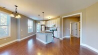 Located at 3170 Centennial Ridge in Grand Rapids, Michigan, this single-floor home offers a well-designed open-concept layout that seamlessly connects the kitchen, dining, and living areas. The kitchen is a standout feature, showcasing crisp white cabinetry with dark hardware, a curved center island with a built-in sink and pendant lighting overhead, and a full suite of stainless steel appliances including a gas range, over-the-range microwave, and refrigerator. A neutral tile backsplash adds a clean, polished finish. Rich hardwood flooring flows throughout the main living and kitchen areas, while multiple windows allow generous natural light to fill the space. The dining area is illuminated by a classic chandelier and benefits from views of the surrounding neighborhood through large windows. The bedrooms are finished with plush carpet and feature windows that bring in additional natural light, providing comfortable and quiet retreats. The bathrooms include both a full tub-and-shower combo and a dedicated walk-in shower stall, each finished in clean white surrounds with hardwood flooring. Warm, neutral-toned walls throughout create a cohesive and inviting atmosphere across every room in the home.