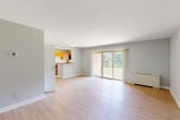 Located at 7400 Parkwood Ct, Unit 202 in Falls Church, VA, this one-bedroom residence offers a well-organized single-floor layout with a clean, modern aesthetic throughout. Light gray walls and light-toned hardwood-style flooring run continuously across all rooms, creating a cohesive and airy feel.

The combined kitchen and living area serves as the heart of the unit. The kitchen is outfitted with warm honey-toned wood cabinetry, granite countertops, stainless steel appliances including a refrigerator, dishwasher, and gas range, and a peninsula that provides additional prep and seating space. A window above the sink brings in natural light. The living area is open and spacious, anchored by large sliding glass doors that lead to a private balcony overlooking lush, tree-lined greenery — a standout feature that adds significant natural light and outdoor connection.

The bedroom is generously sized, featuring a ceiling fan, a window with views of the surrounding brick exterior and mature trees, and a dedicated closet for storage. The neutral palette and light flooring keep the room feeling bright and versatile.

Overall, the unit presents a functional and comfortable layout with practical finishes, abundant natural light, and pleasant outdoor views, making it a well-rounded residential space in Falls Church, VA.