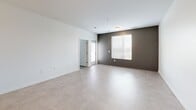 Located at 101 Main St in Lafayette, Indiana, this one-bedroom, one-bathroom unit delivers a thoughtfully designed, modern living experience across a single floor. The open-concept kitchen and living area serves as the heart of the unit, featuring a large peninsula with a white quartz countertop, an undermount sink, and stylish pendant lighting overhead. The kitchen is outfitted with dark wood cabinetry, a subway tile backsplash, and a full suite of stainless steel appliances including a refrigerator, microwave, and range. Large tile flooring flows through the main living area, which is brightened by a wide window with outdoor views and accented by a bold charcoal feature wall. The bedroom offers plush carpet, a generous closet, and a window with natural light. It connects conveniently to the full bathroom, which includes a tub/shower combination, a dark wood vanity with quartz countertop, and tile flooring. The unit also includes a dedicated laundry space with a stacked washer and dryer and built-in shelving. Clean white walls, contemporary hardware, and a neutral color palette give the space a cohesive, move-in-ready aesthetic throughout.
