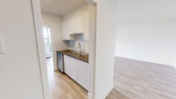 Located on the 12th floor at 1340 Danforth Road in Toronto's Scarborough district, this well-appointed 2-bedroom, 1-bathroom unit offers a generous and thoughtfully laid-out living space. Light wood laminate flooring runs consistently throughout, complementing the clean white walls and creating a bright, cohesive aesthetic.

The expansive living room is a standout feature, with floor-to-ceiling windows and a sliding glass door opening onto a private balcony. Panoramic treetop and cityscape views flood the space with natural light, making it an inviting area for both relaxing and entertaining. Baseboard heating units are positioned beneath the windows throughout the unit.

The spacious primary bedroom features its own window with scenic outdoor views and ample room for furnishings. A dedicated walk-in closet with built-in shelving and hanging rods provides excellent storage. The second bedroom is well-sized, offering a sliding double-door closet and its own window with treetop views.

The bathroom is finished with classic white subway tile surrounding a full soaker tub and shower combination with chrome fixtures, offering a clean and timeless look. A hallway connects the rooms efficiently, contributing to the unit's practical flow. The overall ambiance is clean, modern, and move-in ready.