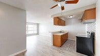 Located on the third floor at 464 S Berendo St in the Koreatown neighborhood of Los Angeles, this one-bedroom, one-bathroom unit offers a well-organized, efficiently designed layout with light-toned wood-style flooring running throughout. The open-concept living and dining area is bright and welcoming, anchored by a large window that allows natural light to fill the space, complemented by a ceiling fan overhead and a textured ceiling finish. A wall-unit heater and A/C provide climate control directly in the living area.

The kitchen is thoughtfully designed with warm honey-toned wood cabinetry, light quartz-style countertops, a double stainless steel sink, and a stainless steel electric range. A mosaic tile backsplash adds a modern decorative touch behind the stove, while a peninsula counter connects the kitchen to the main living space.

The bedroom is a comfortable size, featuring two mirrored sliding-door closets that enhance the sense of space, along with a window fitted with vertical blinds for privacy and light control. Additional closet space is available in the hallway, providing generous storage throughout.

The bathroom is clean and functional, featuring a full-size soaking tub and shower combination, a white vanity with a light countertop, and wood-look tile flooring. The overall palette of neutral grays and whites creates a calm, move-in-ready atmosphere throughout the unit.