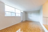 Located at 2250 Kennedy Rd in Toronto's Scarborough district, this 2-bedroom, 1-bathroom unit offers a practical and well-organized layout across a single floor. A defining architectural feature is the split-level living area, where a white metal railing separates a raised section from the main living space below, adding visual interest and a sense of depth to the open area. Large windows in the living room flood the space with natural light and frame pleasant views of surrounding greenery.

Classic parquet flooring is consistent throughout the living areas, hallway, and bedrooms, lending warmth and a timeless character to the unit. The primary bedroom is a comfortable size, featuring a window with tree views and abundant natural light. The second bedroom, though more compact, also benefits from natural light through its own window.

The kitchen is finished with light tile flooring, granite-look countertops, grey cabinetry with gold hardware, a white electric range, and a subway tile backsplash. The bathroom is clean and functional, featuring a full-size soaker tub with an overhead shower, white tile surround, and chrome fixtures. The hallway connects all rooms efficiently, completing this well-structured residential space.