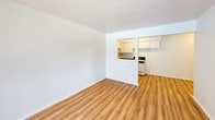 Seaway Terrace Unit 2 is a single-floor, 2-bedroom, 1-bathroom residence featuring a clean, functional layout throughout. Light-toned hardwood-style flooring runs continuously across the living areas and bedrooms, lending a cohesive and well-maintained feel to the space.

The open living area is bright and neutrally finished with white walls, providing a versatile canvas for furnishing. A pass-through opening connects the living room directly to the kitchen, enhancing the sense of openness between the two spaces. The kitchen is efficiently arranged in a U-shaped configuration, featuring white cabinetry, dark granite-style countertops, a single-basin sink, and a white electric range. A window above the counter allows natural light into the cooking area.

Both bedrooms are comparably sized, each offering natural light through windows fitted with vertical blinds and baseboard heating units along the exterior walls. The neutral walls and consistent flooring carry through each room, maintaining a uniform aesthetic.

The bathroom includes a full tub and shower combination with a clean, white surround. Overall, the unit presents a straightforward, well-kept layout suited for comfortable everyday living.