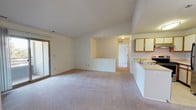 The Wedgewood Classic 2-bedroom, 2-bathroom residence is a single-floor home designed with practical comfort in mind. The open-concept living area features plush carpeting and connects seamlessly to the kitchen via a peninsula counter, creating an inviting, functional space. A sliding glass door allows natural light to fill the living area and provides outdoor access. The kitchen is well-appointed with wood-trimmed cabinetry, a stainless steel refrigerator, an electric range, a double-basin sink, and ample counter space. A pass-through counter further enhances the connection between the kitchen and living areas. Both bedrooms are generously sized, carpeted, and filled with natural light from large windows that offer pleasant views of surrounding greenery. The primary bedroom includes direct access to a full en-suite bathroom and a walk-in closet, while an additional full bathroom serves the second bedroom and guests. Both bathrooms feature tile flooring, a soaking tub with tiled surround, and a vanity with a wide mirror. A dedicated laundry area with a stacked washer and dryer adds everyday convenience. The overall design is clean, neutral, and move-in ready.