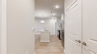 This thoughtfully designed 1-bedroom, 1-bathroom residence offers a cohesive, modern aesthetic across its single floor. Light wood-style flooring flows seamlessly through the open-concept living and kitchen areas, creating a bright and airy atmosphere enhanced by recessed lighting throughout.

The kitchen serves as a functional centerpiece, anchored by a central island with a granite countertop and undermount sink, illuminated by a pendant light above. Gray shaker-style cabinetry with brushed hardware lines the walls, complemented by matching granite countertops, a tile backsplash, and stainless steel appliances including a refrigerator, electric range, and built-in microwave.

The living room is an open, well-lit space with recessed lighting, neutral walls, and access to an exterior door with an adjacent window, allowing for natural light and outdoor views. The bedroom features plush carpeting, a ceiling fan, and multiple windows that bring in ample natural light while offering exterior views.

The bathroom is generously proportioned, showcasing an extended gray vanity with dual mirrors, granite countertops, and light wood-style flooring that mirrors the main living areas. A soaking tub and dedicated closet space complete the suite. Additional storage is provided by a hallway closet, rounding out a practical and polished living space.