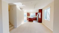 This two-floor home offers a thoughtfully designed layout that balances open communal spaces with comfortable private areas. The main level features an expansive open-concept living and dining area finished with plush neutral carpeting, bathed in natural light from multiple windows and a sliding glass door that invites outdoor views. A wide archway connects the living space seamlessly to the kitchen.

The kitchen is a standout feature, showcasing rich dark cherry wood cabinetry, light countertops, and a mosaic tile backsplash with warm tones. A central island provides additional workspace and casual seating, while a full suite of stainless steel appliances — including a gas range, built-in microwave, dishwasher, and French door refrigerator — completes the space. Hardwood flooring and pendant lighting add to the kitchen's polished character. A large window over the sink fills the area with natural light and offers pleasant outdoor views.

The bathrooms are clean and functional, with one featuring a glass-enclosed walk-in shower with white tile surround and another offering a full tub-shower combination with chrome fixtures. Closets throughout the home are well-sized, including a large walk-in closet with wraparound shelving and hanging rods, providing excellent storage capacity across both floors.