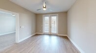 Located at 222 S Main St in Mooresville, NC, this well-appointed one-bedroom, one-bathroom unit offers a thoughtfully designed single-level layout that maximizes every square foot of its compact footprint. Light-toned hardwood-style flooring flows consistently throughout the space, creating a cohesive and clean aesthetic.

The open-concept kitchen serves as a functional centerpiece, featuring a large island with a built-in stainless steel sink, quartz countertops, and pendant lighting overhead. A full suite of stainless steel appliances — including a side-by-side refrigerator with ice and water dispenser, electric range, built-in microwave, and dishwasher — is complemented by two-tone cabinetry with white uppers and warm wood-toned lowers.

The living room is bright and airy, with large windows topped by transom panels that invite natural light, along with a ceiling fan for added comfort. French doors open to an outdoor area, further enhancing the sense of openness. The bedroom is generously proportioned and features its own ceiling fan and neutral wall tones.

The bathroom is elegantly elongated, with a wide vanity offering ample counter space, a glass-enclosed shower, and consistent flooring that ties the space together. A hallway provides a clean transition between rooms, completing this efficiently designed and modern residential unit.