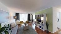 Located at 4710 Bethesda Avenue, Unit 505 in Bethesda, MD, this single-floor residence combines contemporary design with functional living. The expansive open-concept living area is anchored by rich parquet wood flooring and flooded with natural light through floor-to-ceiling sliding glass doors that lead to a private balcony. The living space is thoughtfully arranged to accommodate multiple seating and dining zones, separated by a sleek white open-shelving unit that also houses a flat-screen TV. An accent wall adds a striking visual element alongside curated artwork throughout. The kitchen features white cabinetry, a gas range, ample counter space, and a built-in sink, providing a clean and efficient layout. The primary bedroom is a serene retreat highlighted by a bold textured accent wall, warm parquet floors, and generous natural light from a large window. The second bedroom offers ample closet space with full-length bi-fold doors and tasteful wall art. A clean, tiled bathroom with a shower-tub combination completes the layout. Throughout the residence, a cohesive, modern aesthetic is maintained with neutral tones, carefully chosen furnishings, and artistic accents that create an inviting and sophisticated ambiance.