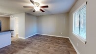 Located at 100 Horizon Ct NW in Concord, North Carolina, this efficiently designed one-bedroom, one-bathroom unit offers a practical and comfortable layout across a single floor. The combined kitchen and living area forms the heart of the unit, where wood-look flooring flows throughout. The kitchen features white cabinetry, dark countertops, a double basin sink, and black appliances including a range and refrigerator, all organized around a peninsula counter that opens to the living space. The living room is bright and airy, with a ceiling fan and a sliding glass door framed by vertical blinds that invite natural light and provide views of the surrounding greenery outside. The bedroom is a well-proportioned retreat finished with plush carpet, a ceiling fan, a window with blinds, and a double-door closet for ample storage. The bathroom is neatly appointed with a white vanity, dark countertop, an illuminated mirror, and wood-look flooring that ties back to the main living areas. Throughout the unit, textured ceilings, neutral-toned walls, and clean white baseboards contribute to a cohesive and understated aesthetic, making the space functional and move-in ready.