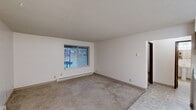 Located at 2614 E 27th Ave in Spokane, WA, this one-bedroom, one-bathroom unit offers a practical and efficiently organized single-floor layout. The living area features neutral carpet flooring, white walls, and a textured ceiling, with a large window dressed in vertical blinds that allows natural light to fill the space. A baseboard heating system runs along the perimeter, providing reliable warmth throughout. The transition from carpet to tile flooring marks the entry into the kitchen and other hard-surface areas. The kitchen is equipped with warm oak cabinetry offering ample upper and lower storage, light-colored countertops, a double-basin sink, and white appliances including an electric range and a full-size refrigerator. Tile flooring and fluorescent overhead lighting give the kitchen a clean, functional feel. The bedroom is a comfortable size, featuring carpet flooring, a window with vertical blinds, baseboard heating, and access to a dedicated closet. The bathroom is finished in a bright, neutral palette with tile flooring, a pedestal sink, a mirrored medicine cabinet with overhead lighting, a toilet, and a tub-shower combination with a grab bar — a practical and accessible design. Overall, the unit presents a clean, no-frills living space well-suited for those seeking functionality in a convenient Spokane location.