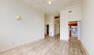 Located at 900 West Marshall Street in Richmond, Virginia, this 2-bedroom, 1-bathroom unit showcases a compelling blend of industrial character and modern comfort. The open living area immediately impresses with soaring ceilings that reveal exposed pipes and structural elements — hallmarks of a converted warehouse building. Light wood-tone flooring runs throughout the main living space, complemented by wall-mounted sconce lighting and a ceiling fan. Large, multi-pane warehouse-style windows flood the space with abundant natural light and offer views of the surrounding neighborhood. The kitchen features warm wood cabinetry, tile flooring, and a full suite of white appliances including a refrigerator, range, microwave, and dishwasher. Both bedrooms are carpeted and generously proportioned, with the primary bedroom benefiting from soaring ceilings, a double-door closet, and bright window exposure. The exposed brick accent walls in the bedroom areas further reinforce the building's industrial heritage. The full bathroom includes tile flooring and a wood-tone vanity. A dedicated laundry room houses a full-size washer and dryer with overhead wire shelving for storage. A hallway and staircase complete the layout, connecting each area of this characterful urban residence.