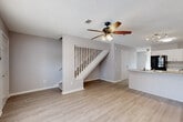 This two-story home on Royal Hills Drive in Pensacola, Florida offers a functional and well-organized layout spread across two levels. The main floor features an open living area with light wood-style luxury vinyl flooring, neutral gray walls, and a textured ceiling with a ceiling fan overhead. A staircase with white balusters connects the two floors, and the layout flows naturally into the kitchen and dining area.

The kitchen is equipped with white cabinetry featuring arched door detailing, light-toned countertops, a stainless steel sink, and black appliances including a refrigerator, electric range, and dishwasher. A track lighting fixture provides task illumination, and the space opens toward the living and dining areas.

The upper level houses the bedrooms, each finished with plush carpeting, neutral walls, ceiling fans with light fixtures, and windows that allow natural light. The bathrooms feature white vanities, full tub-shower combinations, and light, clean finishes throughout.

The home maintains a cohesive, understated aesthetic with consistent neutral tones, practical flooring choices on the main level, and comfortable carpeting upstairs, making it a well-rounded residential space in the Pensacola area.