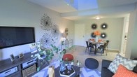 Located at 700 S Reed Ct in Lakewood, Colorado, this single-floor residence offers a thoughtfully designed open-concept layout that seamlessly connects the living and dining areas, creating a cohesive and functional living environment. The living space is anchored by a media wall and complemented by distinctive decorative wall art, including bold starburst accents that add a contemporary flair to the neutral-toned walls. A skylight overhead allows natural light to pour into the room, brightening the interior and highlighting the neutral carpet and tile flooring throughout. The dining area features an industrial-style table and chairs set against similarly styled wall décor, maintaining a consistent modern aesthetic. Colorful accents — including orange floral arrangements and richly textured poufs — add warmth and personality to the space. The layout flows naturally from one area to the next, making it ideal for both everyday living and entertaining. Overall, the space presents a modern, curated atmosphere with a balance of bold decorative choices and clean, neutral architectural elements that give it a bright, inviting character.