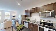 Located at 3688 Brinell St W in Columbus, OH, this one-bedroom, one-bathroom unit offers a thoughtfully designed single-floor layout that maximizes every square foot of living space. The open-concept kitchen and living area form the heart of the unit, with light wood-tone flooring flowing throughout. The kitchen is equipped with rich dark wood cabinetry, granite countertops, a double-basin stainless steel sink, and a full suite of stainless steel appliances, including a range, microwave, dishwasher, and refrigerator. A narrow console table provides a practical dining or prep surface adjacent to the kitchen. The living room is bright and airy, featuring multiple windows that invite natural light and offer outdoor views. Neutral walls and clean lines contribute to a calm, modern ambiance. The bedroom is a comfortable retreat with carpet flooring, warm neutral tones, and dual windows that overlook a balcony, providing both light and ventilation. A dedicated closet offers convenient storage. The bathroom features dark wood vanity cabinetry with granite countertops, wood-look tile flooring, and a walk-in shower with glass sliding doors. Recessed lighting throughout maintains a clean, contemporary aesthetic across the entire unit.
