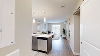 Located on Green Diamond Road in Regina, Saskatchewan, this 2-bedroom, 2-bathroom unit offers a thoughtfully designed single-floor layout that maximizes functionality and comfort. The open-concept living and kitchen area serves as the heart of the home, where light wood-tone flooring flows throughout. The kitchen is equipped with stainless steel appliances — including a refrigerator, stove, and built-in microwave — complemented by crisp white cabinetry, a white quartz countertop, and a navy blue island with bar seating for three, illuminated by sleek pendant lighting. The living area is bright and welcoming, featuring sliding patio doors that invite natural light and provide outdoor access, along with a wall-mounted air conditioning unit. The primary bedroom is a comfortable retreat with a large window fitted with zebra blinds and generous proportions, while the second bedroom offers a cozy, well-lit space with similar window treatments. A dedicated walk-in closet with wire shelving provides ample storage. Both bathrooms are clean and functional, each featuring a full soaker tub with shower combination. The unit presents a modern, neutral palette throughout, making it a practical and inviting living space.