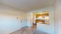 This single-floor unit offers a practical and well-organized layout designed for comfortable everyday living. The living area greets residents upon entry, featuring neutral-toned carpeting and a seamless visual connection to the kitchen through a pass-through opening with a breakfast bar counter. The entry also includes a closet with bi-fold doors for convenient storage.

The kitchen is efficiently laid out with warm oak cabinetry spanning both upper and lower sections, dark granite-toned countertops, a double-basin sink, a gas range with overhead ventilation, and a full-size refrigerator. The kitchen floor is finished in durable stone-look tile, which also extends into the bathroom.

The bedroom is a generously sized, carpeted room featuring a window with blinds that brings in natural light, along with a baseboard heating system and a wall-mounted air conditioning unit for year-round climate control. An exceptionally spacious walk-in closet with built-in shelving and hanging rods provides ample storage.

The bathroom includes a single-sink vanity with wood cabinetry, a wall mirror with overhead lighting, a toilet, and a full bathtub with shower. The tile flooring completes the space with a clean, cohesive look throughout the wet areas.