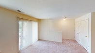 This single-floor residence offers a well-organized layout designed for comfortable everyday living. The spacious living area is bathed in natural light, courtesy of large windows and a sliding glass door fitted with vertical blinds that open to an outdoor view of surrounding greenery. A half-wall partition neatly separates the living space from the adjoining areas, lending a sense of definition without sacrificing openness. Soft, neutral-toned carpeting runs throughout the living and bedroom areas, contributing to a warm and inviting ambiance.

The kitchen is efficiently arranged with warm wood-toned cabinetry providing ample storage, white appliances including a refrigerator and electric range, and a double-basin sink set into a continuous countertop. Pendant lighting overhead adds a functional yet stylish touch, while wood-look flooring grounds the space with durability and easy maintenance.

The bedroom is generously sized, featuring its own sliding glass door that frames a lush, green outdoor view, along with access to a walk-in closet offering substantial storage capacity. The bathroom is clean and practical, with a single-sink vanity topped with a white countertop, wood-toned cabinetry, wood-look flooring, and a shower and tub combination. Throughout the space, neutral wall tones and consistent finishes create a cohesive, move-in-ready environment.