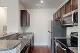 Located at 3214 Central Ave in Charlotte's vibrant Plaza Midwood neighborhood, this well-appointed 2-bedroom, 2-bathroom residence offers a thoughtfully designed single-level layout. The open-concept living area is a standout, featuring rich hardwood flooring, vaulted ceilings with a ceiling fan, and a wall of windows with a glass door leading to a private balcony—flooding the space with natural light and offering pleasant tree-lined views. The kitchen is efficiently designed with dark espresso cabinetry, granite countertops, a double-basin sink, and a full suite of stainless steel appliances including a refrigerator, electric range, and built-in microwave. A peninsula counter creates a natural divide between the kitchen and living area. Both bedrooms are carpeted and tranquil, each with closet storage—the primary bedroom features a spacious double sliding-door closet. The primary bathroom includes a double-sink vanity with dark wood cabinetry and tile flooring, while the second bathroom offers a full tub-shower combination. A hallway and dedicated closet complete the functional layout of this comfortable Charlotte residence.