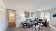 This single-floor, 3-bedroom, 1-bathroom residence offers a practical and comfortable layout designed to maximize functionality. The living room serves as the heart of the home, featuring warm carpet flooring, neutral white walls, and a sliding glass door fitted with vertical blinds that invite natural light and provide access to the outdoors. The space accommodates a full sectional sofa setup and includes entry closets along the front wall for added convenience.

The kitchen is equipped with warm oak cabinetry, white countertops, a stainless steel sink, and a dishwasher, offering ample storage and workspace for everyday cooking needs.

The primary bedroom is a well-sized retreat featuring soft carpet flooring, warm-toned accent walls, and generous closet space. A second bedroom features a soothing light blue accent wall, carpet flooring, and a window for natural light. The third bedroom also offers carpeted floors and closet storage, including a dedicated walk-in style closet with built-in shelving.

The bathroom is clean and bright, featuring a white vanity with an integrated sink, a mirrored medicine cabinet, and chrome fixtures. Two hallways connect the rooms efficiently, contributing to a smooth and logical flow throughout the residence.