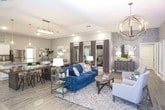 This thoughtfully designed single-floor space combines modern aesthetics with functional layouts, creating an inviting and polished environment throughout. The kitchen is a standout feature, showcasing crisp white shaker-style cabinetry extending to the upper walls, speckled granite countertops, and a full suite of stainless steel appliances including a range, microwave, and refrigerator. A generous island with an integrated sink and pendant lighting above serves as both a practical workspace and a gathering point, while wood-look tile flooring adds warmth underfoot. The open living area exudes a refined, welcoming ambiance, with tray ceilings, recessed lighting, and elegant chandelier fixtures anchoring the space. Neutral gray walls are complemented by textured accent walls and curated artwork, lending depth and character. A comfortable seating arrangement anchors the lounge, making it ideal for both relaxation and social interaction. Adjacent to the living area, a dedicated office space is accessible through a framed interior window, offering a semi-private work environment equipped with a desk and computer workstation. Wood-look flooring flows consistently throughout, tying together each area with a cohesive, contemporary look that is both sophisticated and functional.