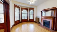 Located at 629 E Franklin Ave in Minneapolis, MN, this compact yet character-rich unit showcases a wealth of historic architectural details. The entrance welcomes visitors with warm hardwood flooring, rich dark wood trim, and a classic paneled door framed by an ornate transom window, setting the tone for the space's vintage charm. A cast-iron radiator provides old-world heating character throughout.

The main living area is a standout, highlighted by an elegant bay window featuring three arched-top panes with dark wood surrounds that flood the room with natural light. A decorative fireplace with a brick hearth and detailed wood mantelpiece serves as a focal point, complementing the light hardwood floors and ceiling fan overhead. Rich wood door casings and baseboards carry consistently through each room.

The kitchen is functional and efficiently laid out, offering oak upper cabinetry, a gas range, a full-size refrigerator, and a single-basin sink — all set against a combination of hardwood and tile flooring. The bathroom includes a full tub-shower combination with clean white tile surround. Throughout the unit, the interplay of original woodwork, arched windows, and classic radiator heating reflects the building's historic Minneapolis roots.