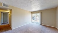 This single-floor unit offers four bedrooms and two bathrooms across a well-organized layout designed to maximize functionality. The combined kitchen and living room serves as the heart of the home, with the kitchen featuring light wood cabinetry, granite-style laminate countertops, a double-basin sink, and durable hardwood-style flooring. The living room is carpeted and bathed in natural light, highlighted by a sliding glass door that opens to a private balcony overlooking a lush outdoor setting — a standout feature of the space.

Each of the four bedrooms is finished with neutral-toned carpet and features closets with bifold doors, providing practical storage. The primary bedroom is generously sized and includes a ceiling fan, adding to the room's comfort. The remaining bedrooms are well-proportioned, with clean walls and textured ceilings consistent throughout the unit.

The two bathrooms are finished with hardwood-style flooring, warm wood vanity cabinetry, and granite-style countertops. A hallway connects the rooms and includes additional closet space. The unit's warm beige color palette, textured ceilings, and consistent finishes throughout create a cohesive and comfortable living environment suited for everyday use.