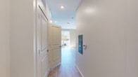 This single-floor unit offers a thoughtfully organized layout that maximizes its compact footprint. Light wood-look flooring runs throughout, providing a clean, cohesive aesthetic that ties the space together. Recessed lighting illuminates each area efficiently, complemented by natural light streaming in through a large sliding glass door that opens to a private balcony, offering outdoor views and a bright, airy atmosphere.

The entry hallway is clean and functional, featuring crisp white trim, a wall-mounted thermostat, and a utility panel, leading seamlessly into the main living area. The open living space is characterized by neutral warm-toned walls and ample room for flexible furniture arrangement.

The kitchen is well-appointed with white shaker-style cabinetry extending to the ceiling for generous storage, stainless steel appliances including a refrigerator, electric range with microwave, and dishwasher. A dedicated in-unit laundry area is tucked conveniently nearby.

The bathroom is finished in a clean, neutral palette, featuring a full-size soaking tub with an overhead shower, brushed nickel fixtures, a toilet, and a vanity with dark countertop detailing. White subway-style wall surrounds keep the space bright and easy to maintain. Overall, the unit presents a modern, move-in-ready interior with practical design throughout.