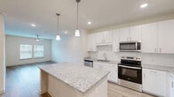 Located at 125 New Hanover St in Beaufort, SC, this well-appointed one-bedroom, one-bathroom unit offers a thoughtfully designed single-floor layout with modern finishes throughout. The open-concept kitchen and living area serves as the heart of the home, anchored by a generous granite-topped island with pendant lighting overhead. The kitchen is outfitted with crisp white shaker cabinetry, a full suite of stainless steel appliances including a refrigerator, electric range, microwave, and dishwasher, and a single-basin sink. Light wood-style flooring flows seamlessly through the main living areas, creating a bright and cohesive aesthetic. The spacious bedroom features a ceiling fan, natural light from dual windows with blinds, and access to a walk-in closet with built-in shelving. The bathroom includes a granite-topped vanity, wood-style flooring, grab bars, and a glass-enclosed shower. A dedicated utility room adds practical convenience to the layout. Neutral wall tones and recessed lighting throughout give the space a clean, contemporary feel well-suited to everyday living in the heart of Beaufort's Lowcountry.